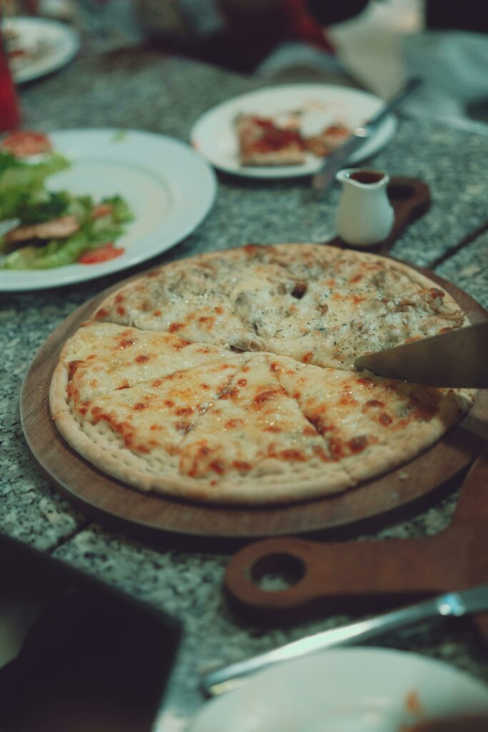 pexels-photo-28263714-28263714 Delicious cheesy pizza served on a rustic table, perfect for casual dining settings.